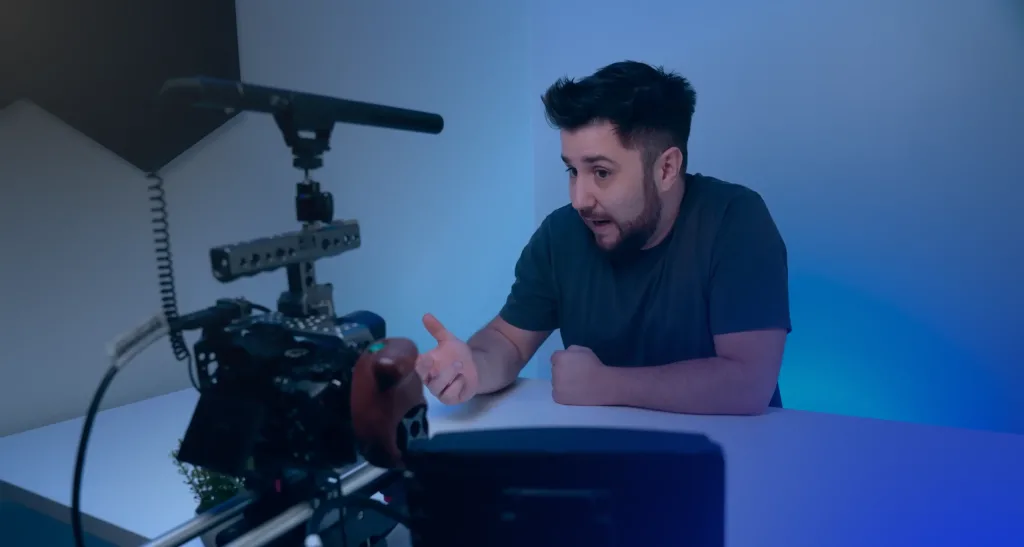 Miguel Pinto Ferreira sentado a uma mesa a falar para uma câmara com microfone, num estúdio com luz azul